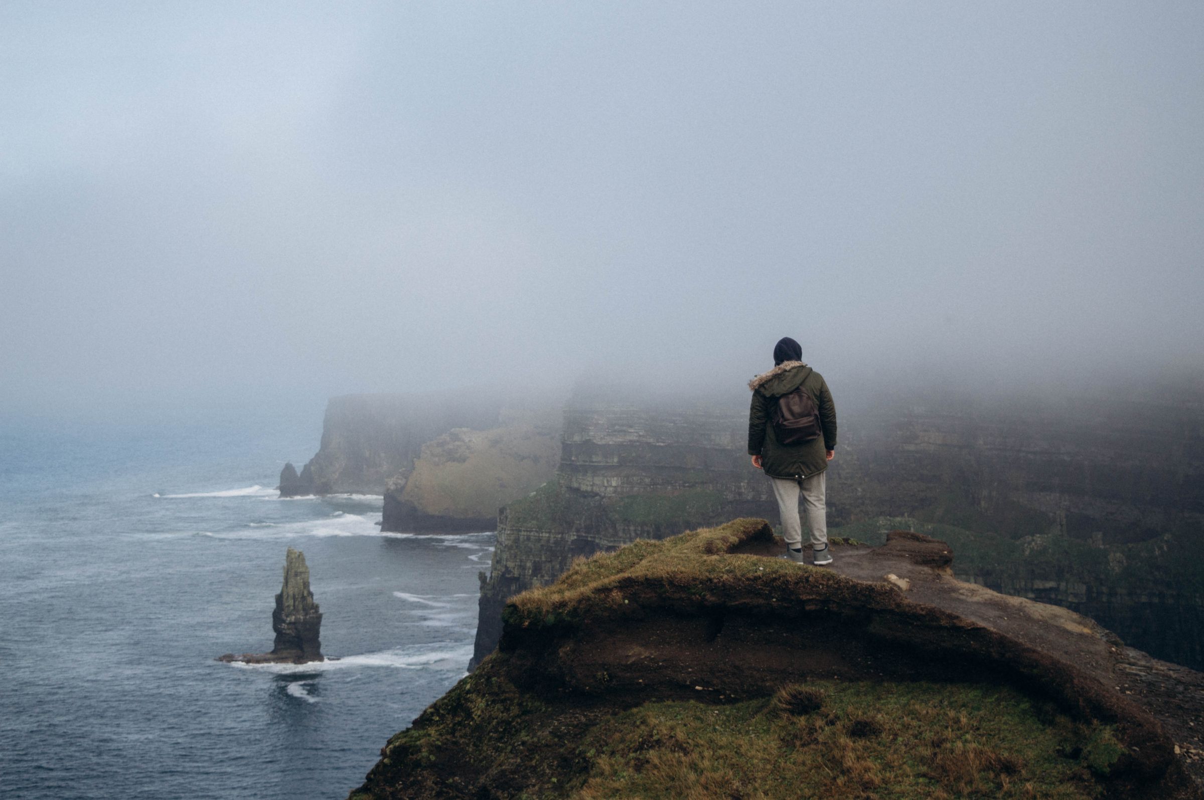 Un praticien de dos, au bord de la falaise, face au brouillard